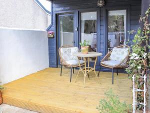 un patio con 2 sillas y una mesa en un porche en Creed Cabin en Stornoway