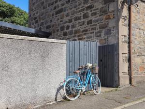 Una bicicleta azul estacionada junto a una pared en Creed Cabin en Stornoway