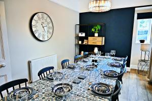 a dining room with a long table with a clock on the wall at Porthmadog, Sleeps 11, 5 Bedrooms, 5 Bathrooms, Mountain Views in Porthmadog