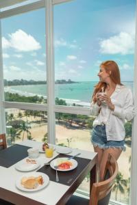 une femme debout devant une table avec de la nourriture dans l'établissement Hotel Brisa Praia Pajuçara, à Maceió