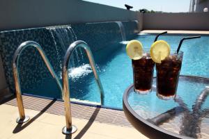 two drinks on a glass table next to a swimming pool at Badi'ah Hotel in Bandar Seri Begawan