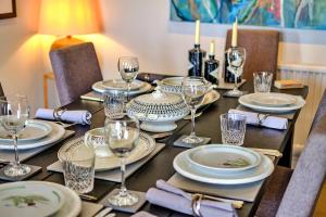 a table with plates and wine glasses on it at Finest Retreats - Kings Wharf - Luxury Riverside Home in Burnham-on-Crouch