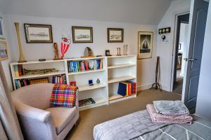 a living room with a chair and a book shelf at Finest Retreats - Kings Wharf - Luxury Riverside Home in Burnham-on-Crouch