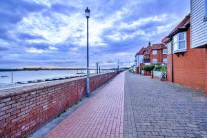 a brick sidewalk next to a brick wall with a street light at Finest Retreats - Kings Wharf - Luxury Riverside Home in Burnham on Crouch