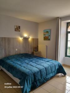 een slaapkamer met een groot bed en een blauwe deken bij Domaine de Meslay, chambres avec salle d'eau et wc in Fyé