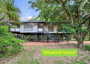 een huis met een veranda en een boom bij Wagait Beach Holiday Houses in Wagait Beach