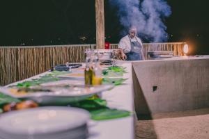 Umbhaba Eco Lodge في هازيفيو: رجل يقف خلف طاولة مع أطباق من الطعام