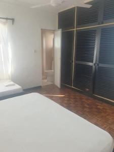 a bedroom with a white bed and a bathroom at Wayside Beach Apartments in Diani Beach