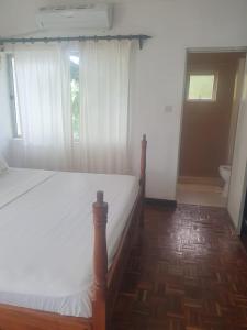 a bedroom with a bed and a window with a toilet at Wayside Beach Apartments in Diani Beach