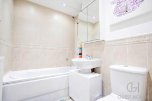 a bathroom with a toilet and a sink and a bath tub at Guest Homes - Calthwaite House in Brough