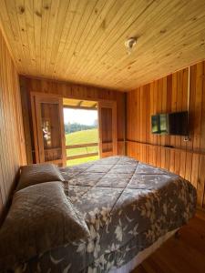 a large bed in a wooden room with a window at CABANAS BELVEDERE SERRA DO RiO DO RASTRO in Lauro Müller