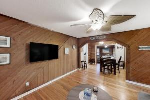 a living room with a ceiling fan and a flat screen tv at Jupiter Pines Cottage in Clearwater