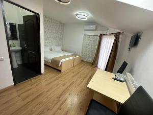 een kamer met een bed, een bureau en een spiegel bij Pensiunea Brici in Cluj-Napoca