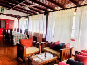 a living room with chairs and a table and windows at Kandyan Holiday Center in Kandy