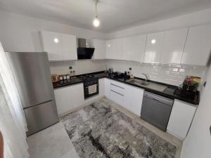 una cocina con armarios blancos y electrodomésticos de acero inoxidable en Bodrum Gündoğan Koyu Havuzlu Site, en Bodrum City