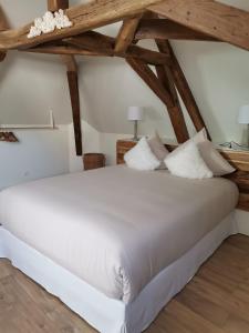 Cette chambre dispose d'un grand lit blanc et de plafonds en bois. dans l'établissement Les Bras de Morphée, à Avize