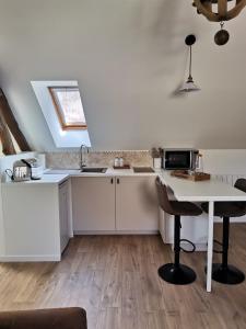 eine Küche mit weißen Schränken, einem Tisch und einem Waschbecken in der Unterkunft Les Bras de Morphée in Avize