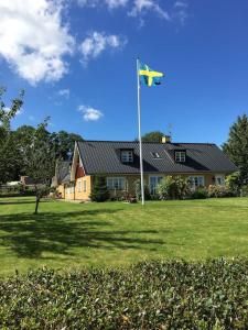 ein Haus mit einer Flagge vor einem Hof in der Unterkunft Gladsax Gamla Gård in Simrishamn