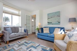 ein Wohnzimmer mit einem blauen Sofa und Stühlen in der Unterkunft York Cottage in Sidmouth