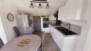 cocina con mesa y cocina con armarios blancos en La colombe en Argelès-sur-Mer