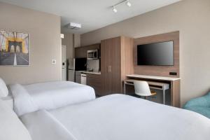a hotel room with two beds and a desk with a tv at TownePlace Suites by Marriott New York Brooklyn in Brooklyn