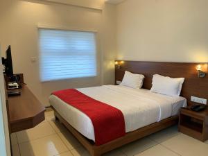1 dormitorio con 1 cama con manta roja y ventana en JESTA RESIDENCY, en Hassan