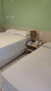 a bedroom with two beds and a night stand with a table at Gran Lençóis Flat in Barreirinhas