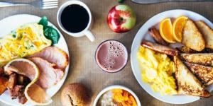 a table with plates of breakfast food and a cup of coffee at Holiday Inn & Suites - Farmington Hills - Detroit NW, an IHG Hotel in Farmington Hills