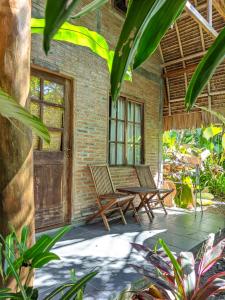a patio with two chairs and a table at Coconut Tree Cottages in Batukaras