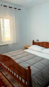 a bedroom with a bed with a wooden frame and a window at Bujtina Kometa in Theth