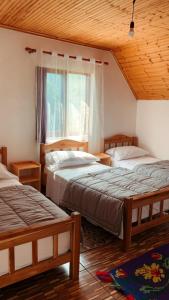 1 dormitorio con 2 camas y ventana en Bujtina Kometa, en Theth