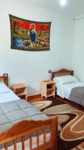a room with two beds and a tapestry on the wall at Bujtina Kometa in Theth