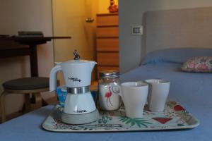 una cafetera y dos tazas en una bandeja en una cama en Il Fenicottero en Cervia
