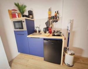 a small kitchen with blue cabinets and a microwave at L'Abri Du Port / MRODBnB in Cancale