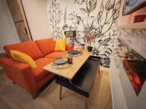 sala de estar con sofá naranja y mesa en L'Abri Du Port / MRODBnB, en Cancale