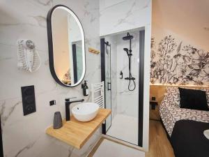 uma casa de banho com um lavatório, um espelho e uma cama em L'Abri Du Port / MRODBnB em Cancale