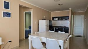 a kitchen with a white table and white chairs at CONDOR Patagonia Aparts in El Calafate
