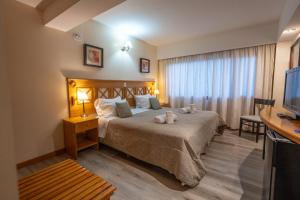 Habitación de hotel con cama y TV en Altos Ushuaia Hotel & Resto en Ushuaia