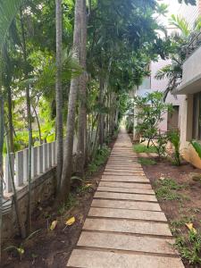 a pathway with palm trees and a building at BareFootBay - Villa with Private Beach Access in Chennai