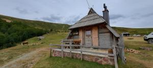 a small wooden house in a field with a fence at Eko katun Vranjak, koliba 28 in Vranjak