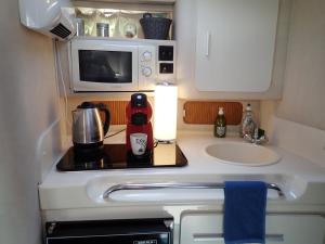 a small kitchen with a sink and a microwave at yacht vedette Arlequin in Gruissan