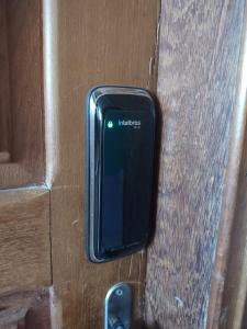 een zwarte mobiele telefoon die uit een houten deur steekt bij Residencial Isaura in Rio Branco