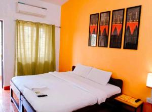 um quarto com uma cama branca e uma parede laranja em Baga Sea Link em Baga