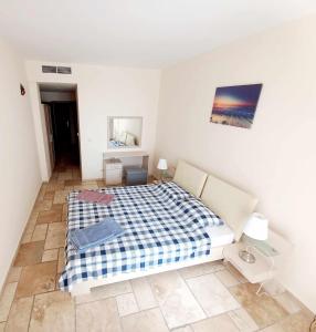a bedroom with a bed with a plaid blanket at Apartament Vallarta in Kavarna