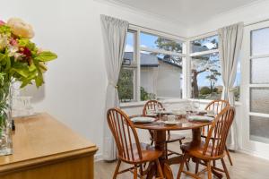 a dining room with a table and chairs and windows at Sunny Beach Holiday Home 80 in Kingston Beach