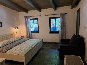 1 dormitorio con 1 cama, 1 silla y 2 ventanas en Penzion U vinaře, en Velké Bílovice
