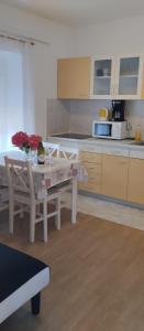 a kitchen with a white table and chairs and a table at Apartmani Gero in Lopar