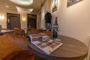 a wooden table with two glasses and a bottle of wine at City Hotel Miskolc in Miskolc