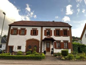 a large white house with wooden shuttered windows at Ferienwohnung Göttert – Haus Erika in Beckingen