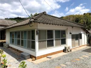 BEACH HOUSE OHAMA - Vacation STAY 76214v في Kuranomoto: منزل أبيض صغير مع الكثير من النوافذ